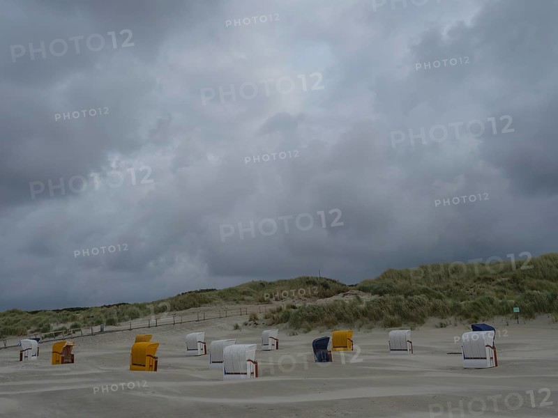 Dune landscape with beach chairs under a grey, stormy sky, colourful beach chairs on the beach and in the dunes under an overcast sky by the sea, Juist, Germany, Europe