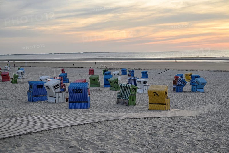 Atmospheric evening sun on a quiet beach with colourful beach chairs and a wooden walkway in the sand, many colourful beach chairs on a balmy summer evening by the sea, langeoog, germany