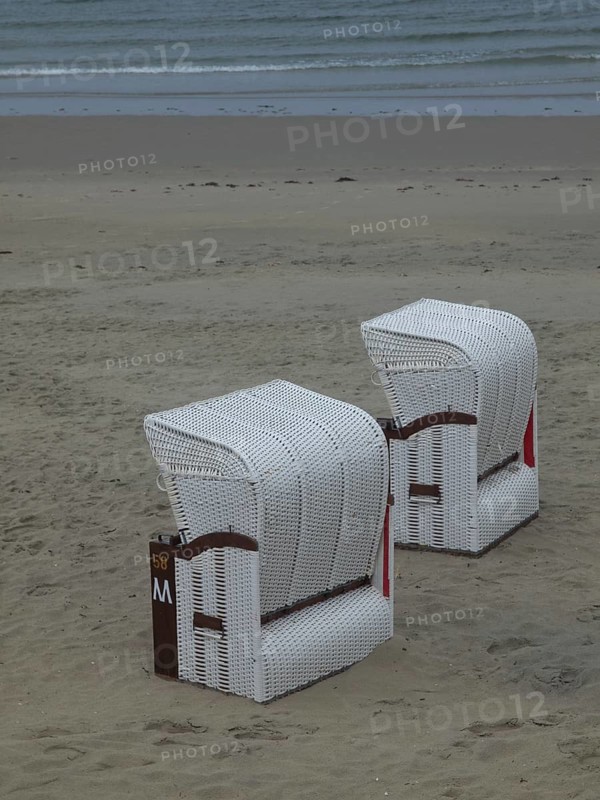 Two white beach chairs stand abandoned on a quiet beach in front of a cloudy sky, beach chairs and beach tents by the sea under a cloudy sky, boardwalk in the sand, Borkum, germany