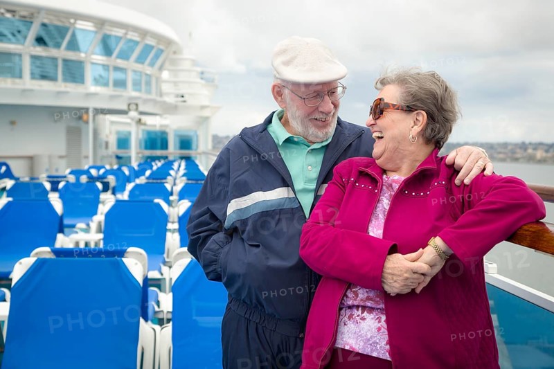 Senior adult couple enjoying the view from their passenger cruise ship railing