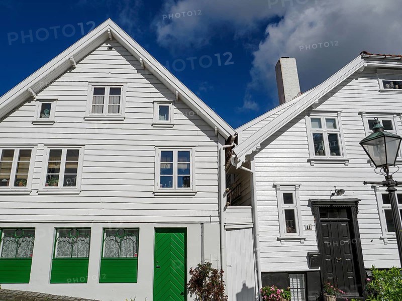 Historic white wooden houses with green doors and windows under a blue sky, illuminated during the day, white wooden houses with green trees and flowers against a blue sky, Stavanger, Norway, Europe