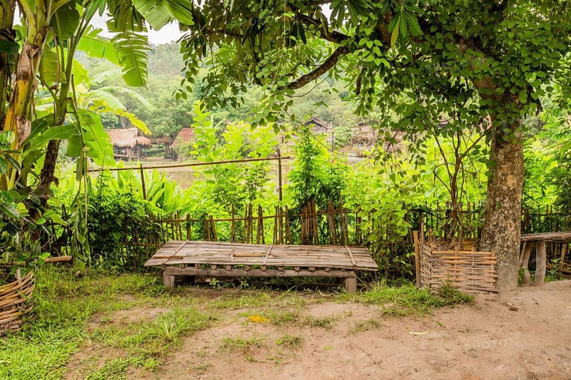Wooden table in front of bamboo fence in small southeast Asian farming community in Chiang Khan, Thailand, Asia