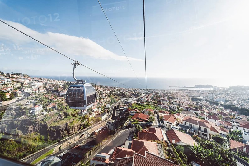 Aerial cableway above a coastal town with a view of the sea and the horizon. Madeira, Portugal, Europe