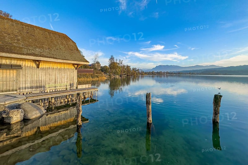 Boathouse on Lake Sempach with reflection in the water and clear sky, Sempach, Lucerne, Switzerland, Europe