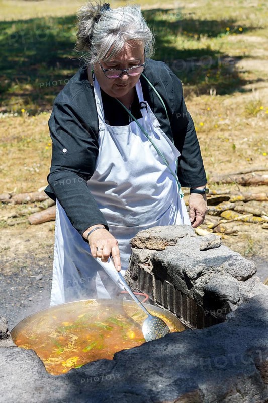Woman cook with white apron cooking a typical Spanish paella on the fire in the countryside