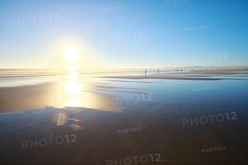 Atlantic ocean sunset with sun and surging waves at wide sand of Fonte da Telha beach, Costa da Caparica, Portugal, Europe