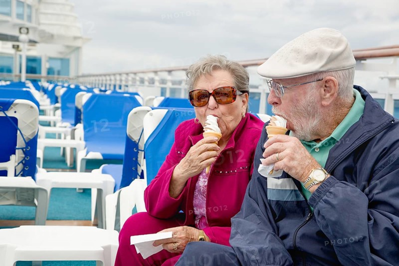 Happy senior adult couple enjoying ice cream on the deck of a luxury passenger cruise ship
