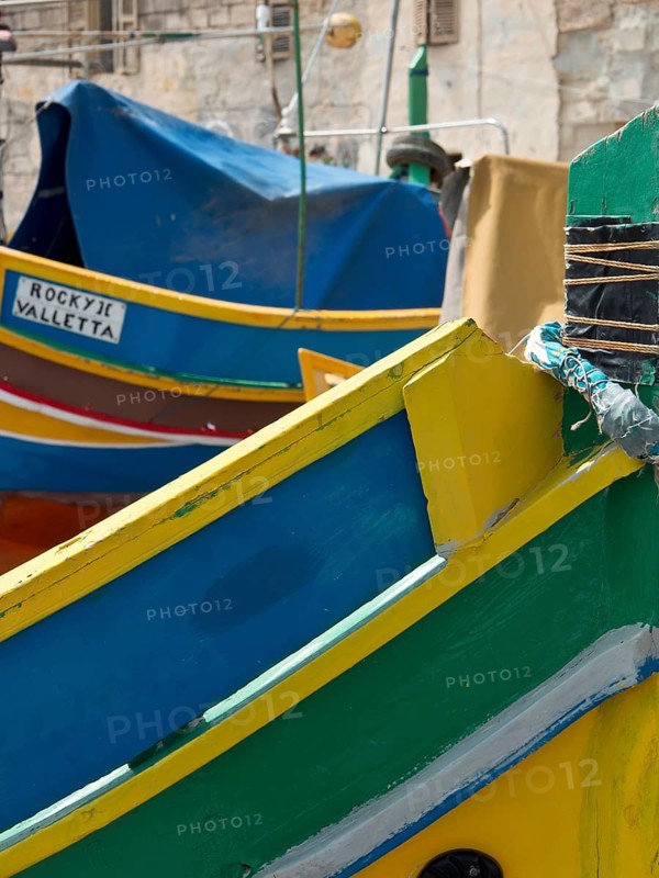 Colourful painted fishing boats in a mediterranean harbour area with name sign 'ROCKY JOE VALLETTA', many colourful fishing boats in a harbour in the mediterranean sea, Marsaxlokk, malta
