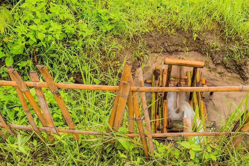 Water flowing from irrigation pipe spinning a small water wheel in canal in Chiang Khan, Thailand, Asia
