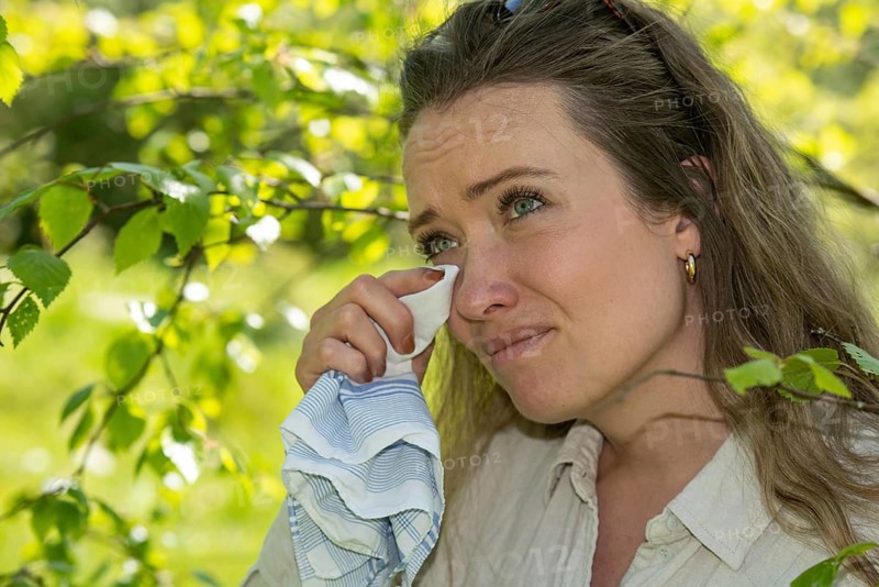 Young Caucasian woman, 35 years old, with allergy stands by flowering birch (Betula) in Ystad, Skane, Sweden, Scandinavia, Europe