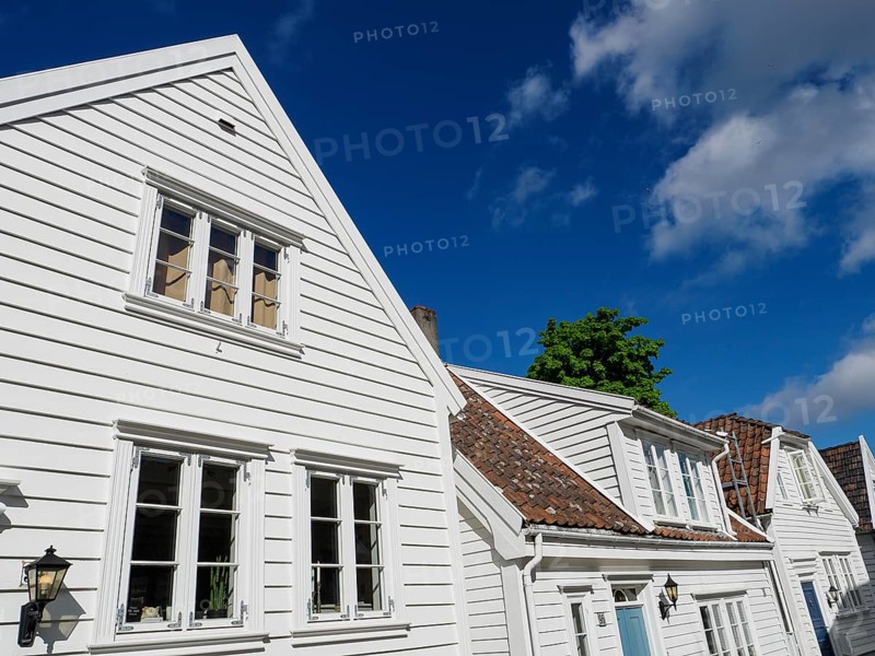 White wooden houses with red roof tiles and windows under a blue sky on a sunny day, white wooden houses with green trees and flowers against a blue sky, Stavanger, Norway, Europe