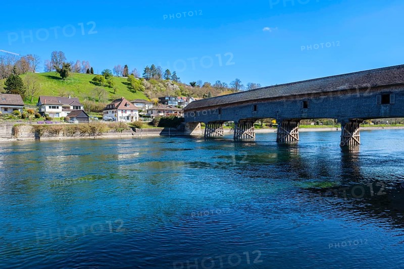 Massive wooden bridge over a clear river, surrounded by houses and green hills, under a blue sky, Diessenhofen, Thurgau, Switzerland, Europe