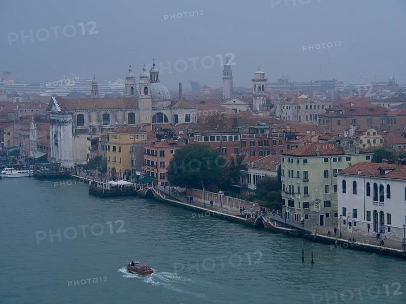 A foggy city view of Venice with historic buildings and boats on the canal, church towers and historic buildings on a large canal, view of Venice from the water, Venice, Italy, Europe
