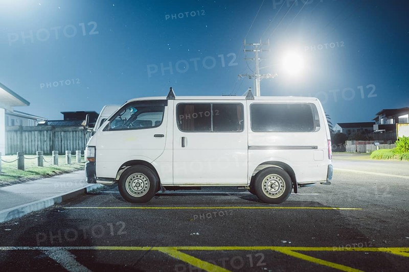White van parked at night under artificial light with stars in the sky
