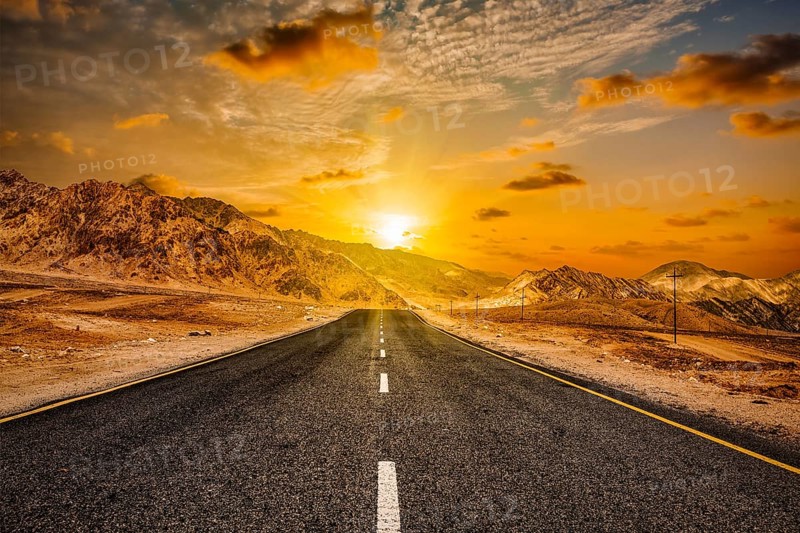 Travel forward concept background, road in Himalayas with mountains and dramatic clouds on sunset. Ladakh, Jammu and Kashmir, India, Asia