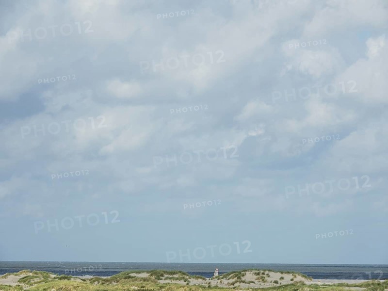 Lonely coastal area with cloudy sky and sea view, lonely beach with dune grass in the neighbouring dunes and marker posts, clouds playing in the sky, Spiekeroog, Germany, Europe