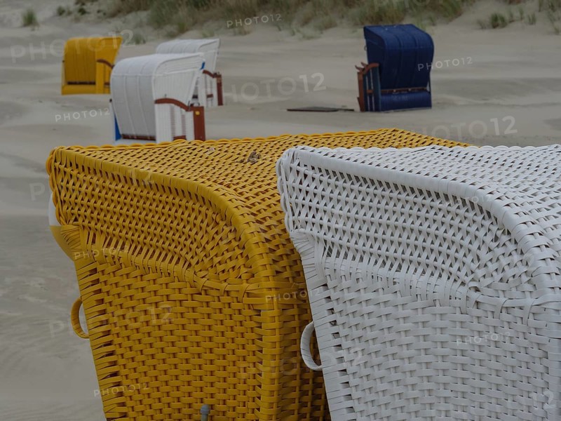 Close-up of yellow and white beach chairs on a sandy beach in cloudy weather, colourful beach chairs on the beach and in the dunes in cloudy weather by the sea, Juist, Germany, Europe