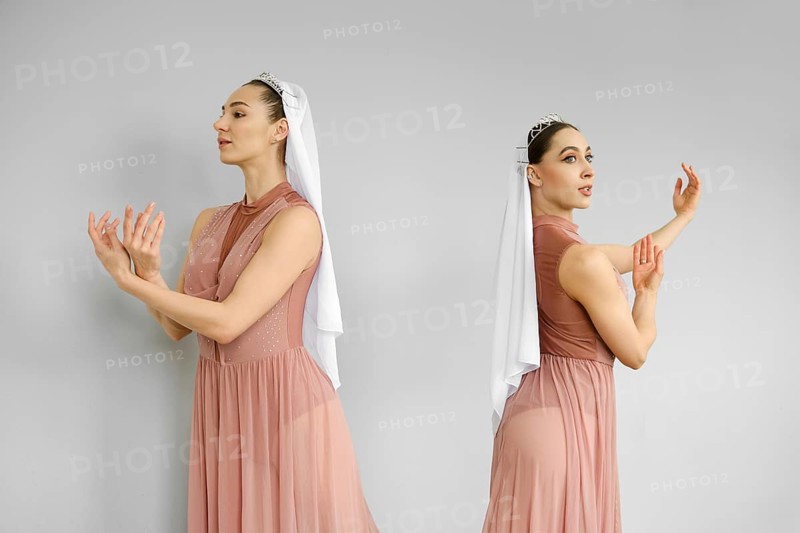 Two ballerinas standing on grey background and perform hand and palms movements