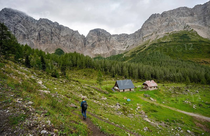 Mountaineer on a hiking trail near a mountain pasture, Obere Wolayer Alpe, Karnischer Hoehenweg, rocky mountain peaks of the Carnic main ridge, Carnic Alps, Carinthia, Austria, Europe