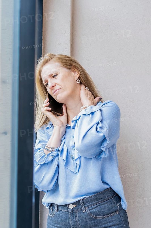 Tired woman talking on the phone with neck pain