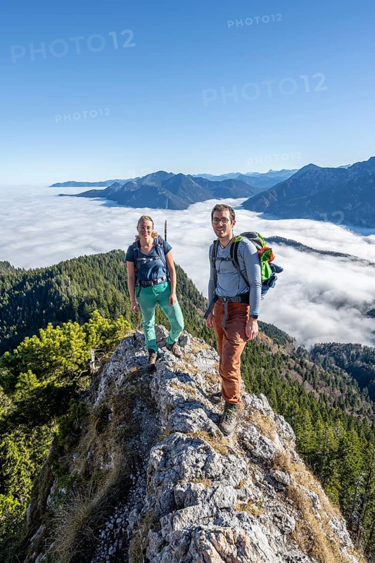 Two hikers at Ettaler Manndl, view over mountain landscape and sea of clouds, high fog in the valley, Ammergau Alps, Bavaria, Germany, Europe