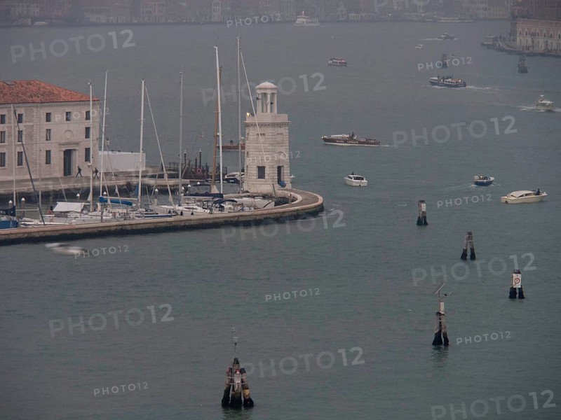 Venice harbour with numerous boats and yachts and a harbour wall in a foggy atmosphere, church towers and historic buildings on a large canal, view of Venice from the water, Venice, Italy, Europe