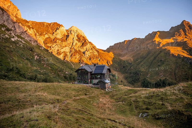 Alpine club hut, Hochweisssteinhaus mountain hut, mountain landscape with green mountain meadows and rocky peaks at sunrise, alpenglow, Carnic High Trail, Carnic Main Ridge, Carnic Alps, Carinthia, Austria, Europe