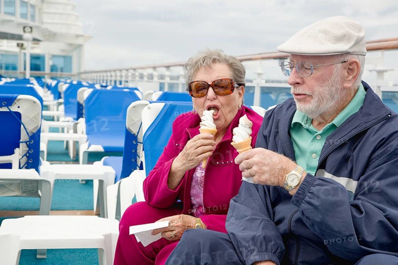Happy senior adult couple enjoying ice cream on the deck of a luxury passenger cruise ship