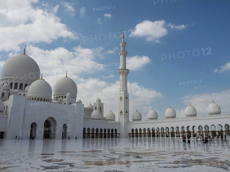 Mosque with a large courtyard, white domes and a high minaret under a slightly cloudy sky, large mosque with white domes and large minarets, abu dhabi, arab emirates