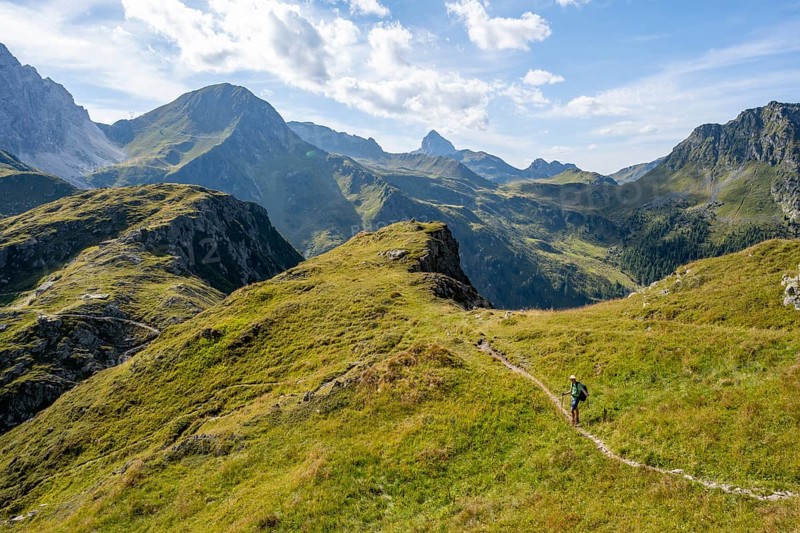 Mountaineer on a hiking trail on a grassy mountain ridge, idyllic mountain landscape with green mountain meadows, descent from Baerenbadegg, Carnic High Trail, Carnic Main Ridge, Carnic Alps, Carinthia, Austria, Europe