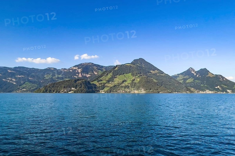 Calm lake under a clear blue sky with picturesque mountains in the background, Beckenried, Nidwalden, Switzerland, Europe