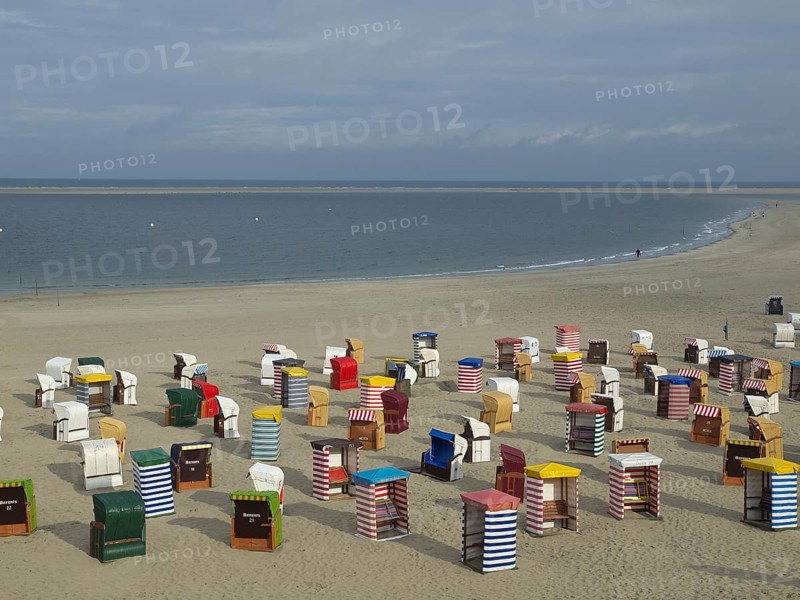 View of numerous colourful beach chairs on the wide beach under a cloudy sky, beach chairs and beach tents by the sea under a cloudy sky, boardwalk in the sand, Borkum, germany