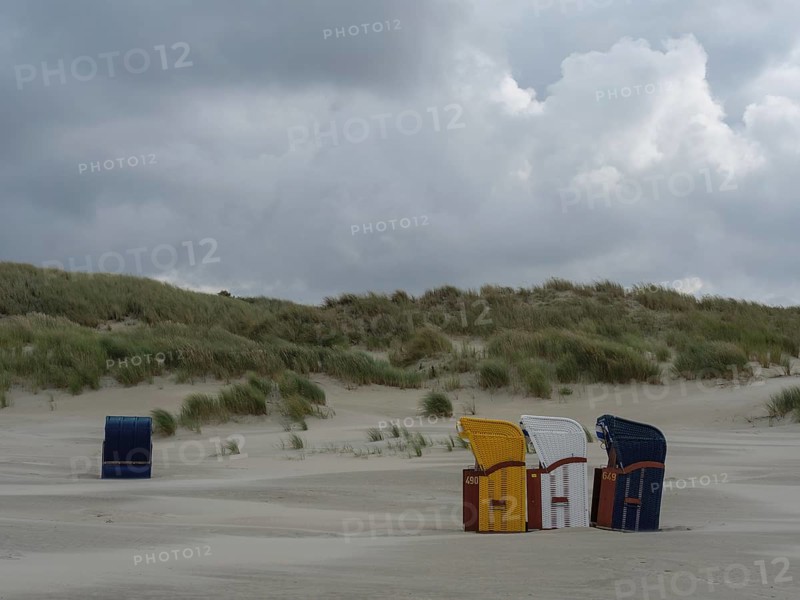 Scattered beach chairs and grey sky over a deserted beach, colourful beach chairs on the beach and in the dunes under an overcast sky by the sea, Juist, Germany, Europe