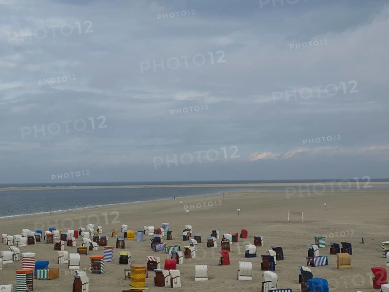 Colourful beach chairs spread out on the wide, sandy beach under a cloudy sky with a view of the sea, beach chairs and beach tents by the sea under a cloudy sky, boardwalk in the sand, Borkum, germany