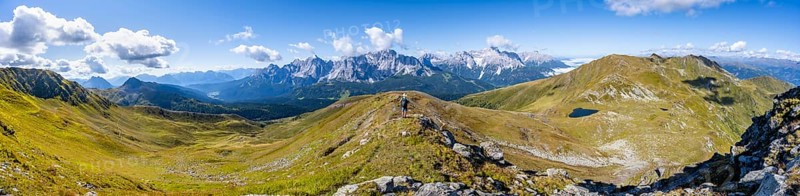 Panorama, mountaineer on a hiking trail between green mountain meadows on a mountain ridge, mountain panorama, view of rocky mountain peaks of the Sesto Dolomites, Carnic Main Ridge, Carnic High Trail, Carnic Alps, Carinthia, Austria, Europe