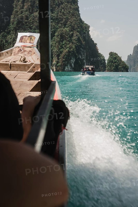 View over a passenger's shoulder of the sea and rocky cliffs. Khao Sok National Park, Thailand, Asia