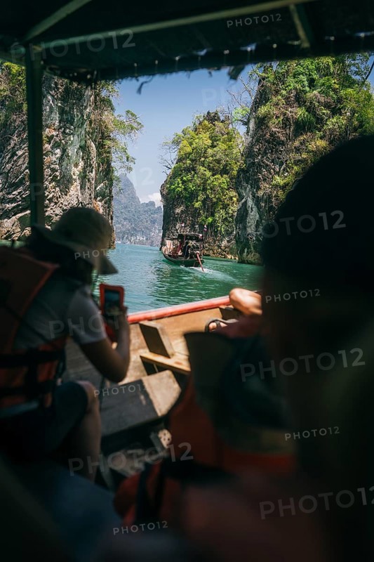 Travellers on a boat experience a sunny boat trip between rock formations. Khao Sok National Park, Thailand, Asia