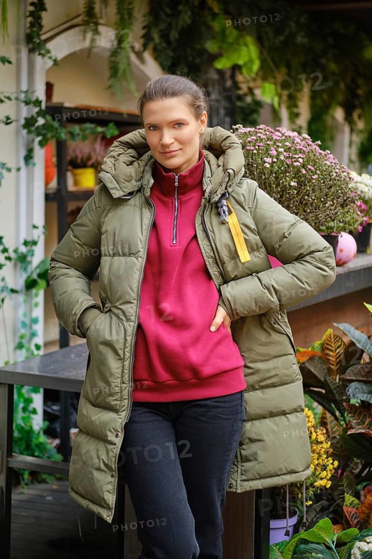 Gardener woman standing at a display case with potted autumn flowers