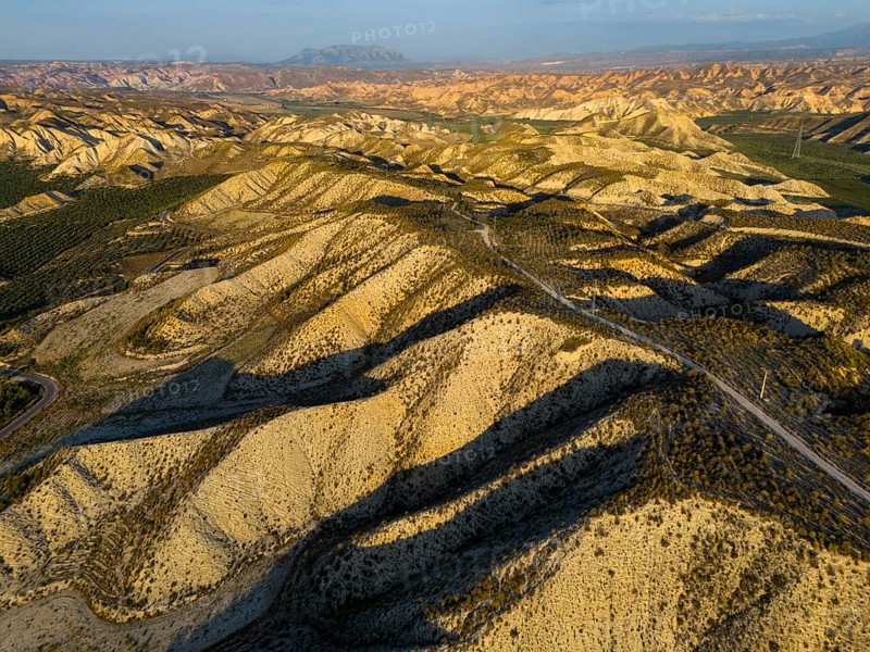 Aerial view of a mountainous desert landscape with shadows and golden lighting at sunset, Dehesas de Guadix, Gorafe Desert, Granada, Andalusia, Spain, Europe