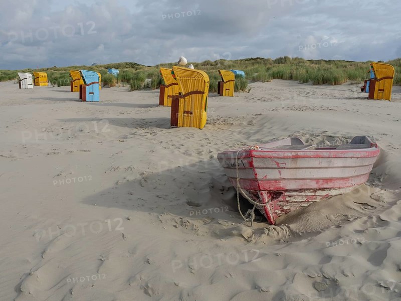 Empty boat on the beach with surrounding beach chairs and dunes, under a cloudy sky, colourful beach chairs on the beach and in the dunes under an overcast sky, red wooden boat and yellow beach chair, Juist, Germany, Europe