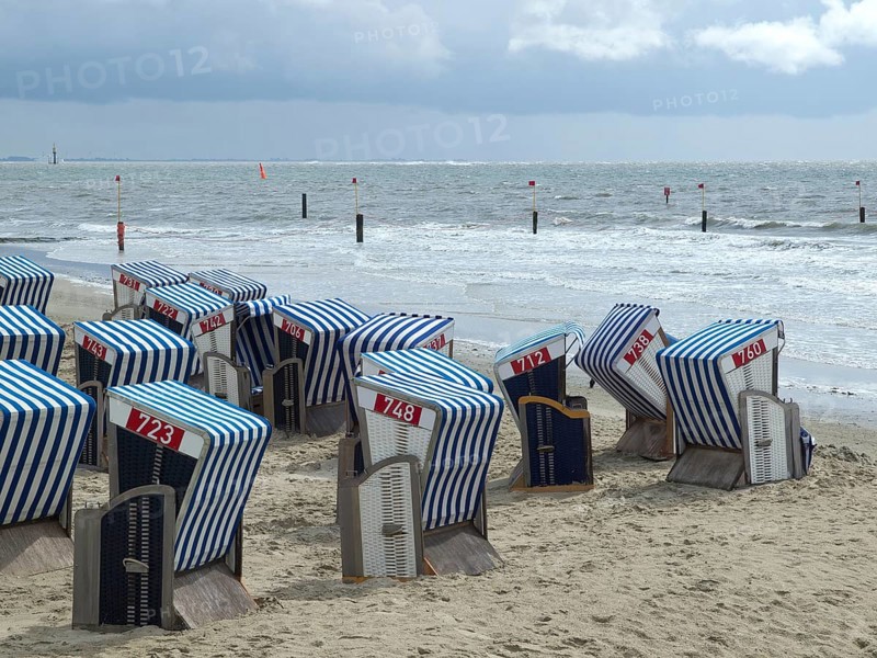 Blue and white beach chairs on a sandy beach with a view of the sea and a cloudy sky, blue and white striped beach chairs on the sea beach, Norderney, Germany, Europe