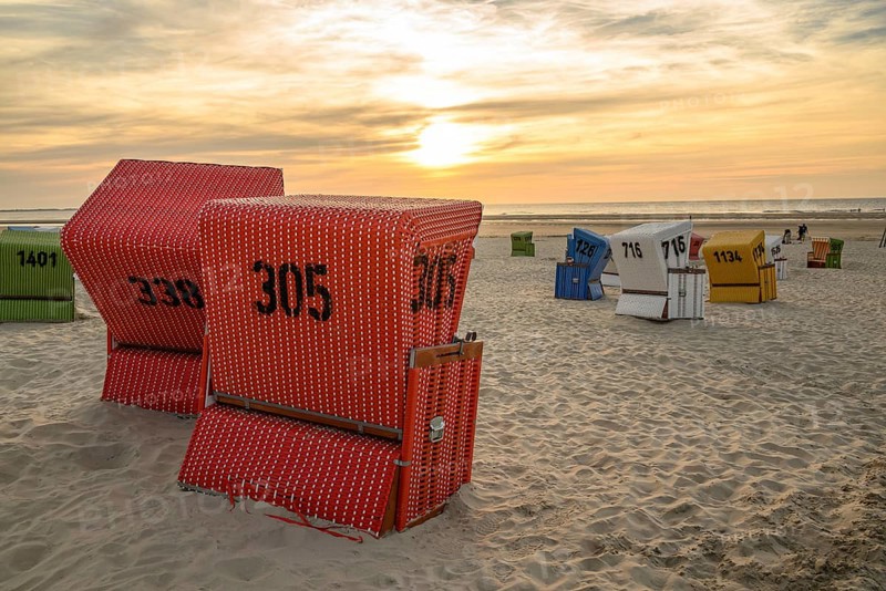 Several beach chairs on the beach at sunset, focus on red baskets, many colourful beach chairs on a warm summer evening by the sea, langeoog, germany