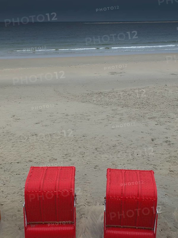 Two red beach chairs stand on an empty beach in front of a calm sea under a cloudy sky, beach chairs and beach tents by the sea under a cloudy sky, boardwalk in the sand, Borkum, germany