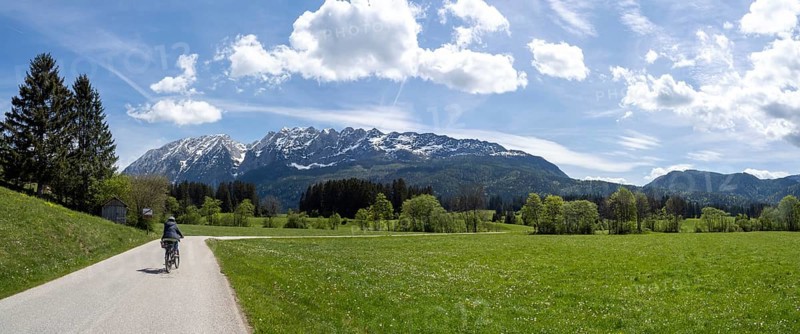 Cyclist on the Ennstal cycle path, path leads through meadows, behind her the Grimming, panoramic view, near Irdning, Styria, Austria, Europe
