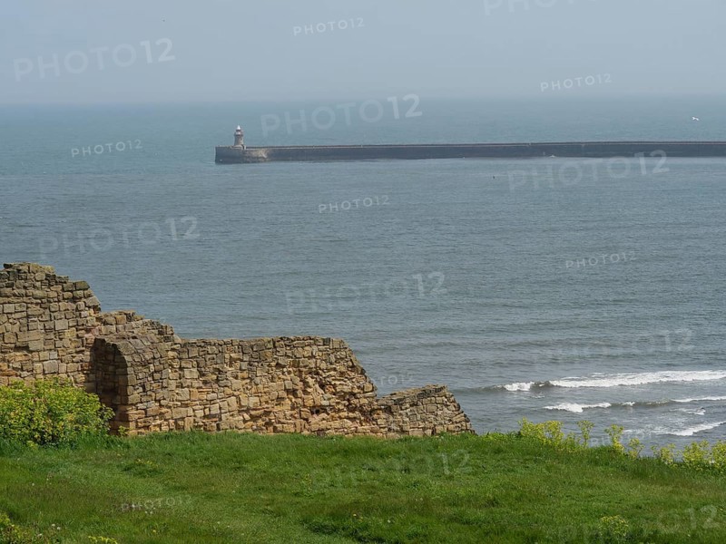 A piece of coastline with ruinous architecture in the foreground and the sea in the background, under a cloudy sky, ruins and old stone walls by the sea, green fields with ruins, Newcastle, England, United Kingdom, Europe
