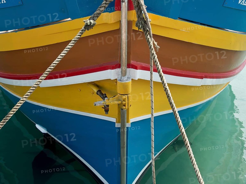 Colourful bow of a boat moored with ropes, on calm water in the harbour, many colourful fishing boats in a harbour in the Mediterranean Sea, Marsaxlokk, malta
