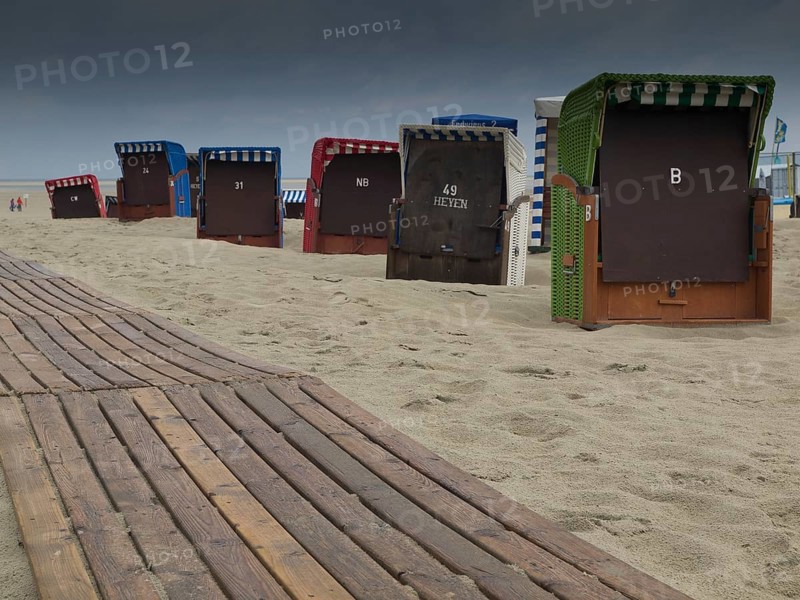 Beach chairs and a wooden jetty on the beach with a cloudy sky and a view of the sea, beach chairs and beach tents by the sea with a cloudy sky, boardwalk in the sand, Borkum, germany
