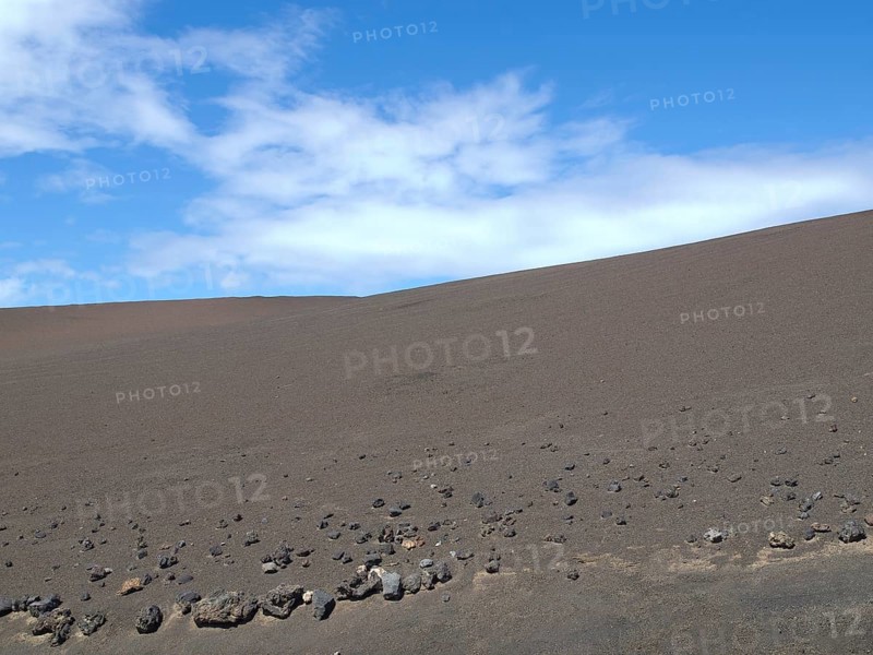 Vast desert landscape with blue sky and dry, stony ground, barren landscape of lava mountains, lanzarote, spain