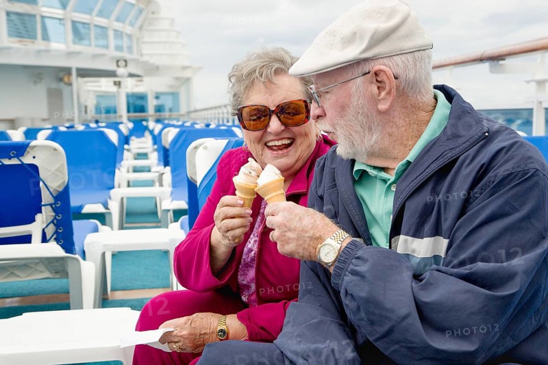 Happy senior adult couple enjoying ice cream on the deck of a luxury passenger cruise ship