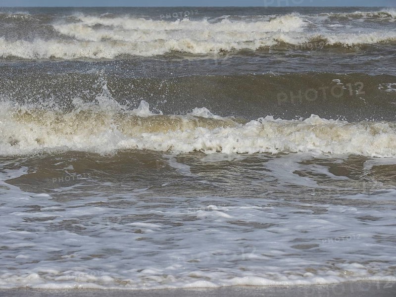 Close-up of churning waves and splashing water in the sea, waves on a beach, sunny day with clouds in the sky over the sea, Spiekeroog, GERMANY